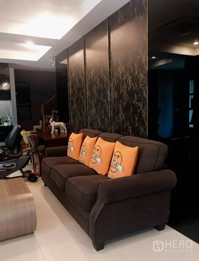 บ้าน ให้เช่าหรือขายในKhan Na Yao, Bangkok - ห้องนั่งเล่นผนังลายหินสีเข้ม โซฟานุ่ม และพื้นที่รับประทานอาหารด้านใน