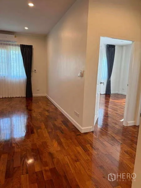 Detached House for rent in Samut Prakan - Hallway with polished wooden floors connecting light-filled bedrooms.