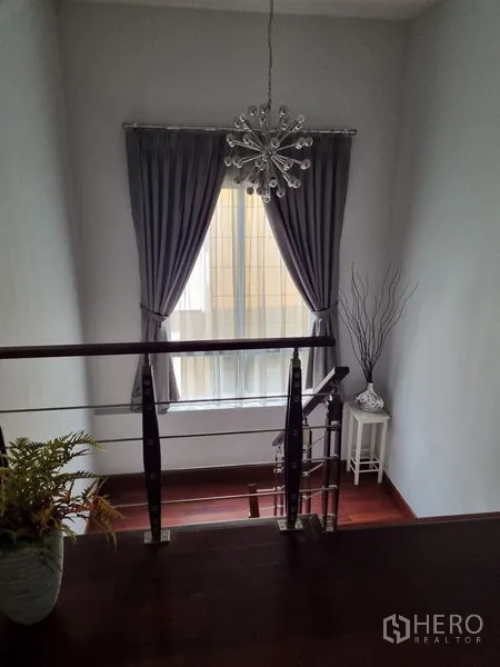 บ้าน ขายในChatuchak, Bangkok - โถงบันไดพร้อมโคมแชนเดอเลียร์ ผ้าม่านสีเทา และราวสแตนเลสไม้