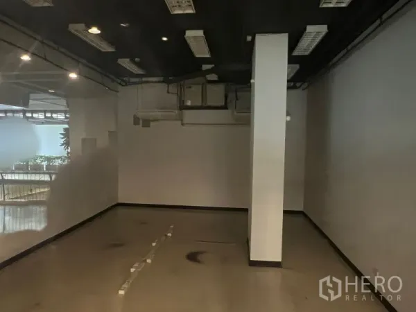 零售空间 出租 - 店内深处视角，中央立柱、外露天花与空调管道。