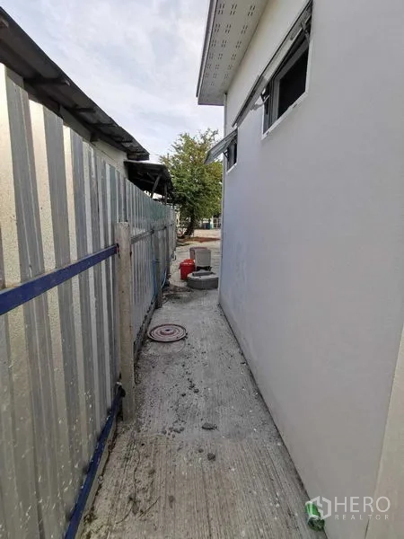 Warehouse for rent in Bang Na, Bangkok - Side passage next to a white building with small ventilation windows