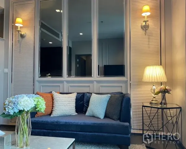 คอนโด ให้เช่าหรือขายในWatthana, Bangkok - มุมนั่งเล่นพร้อมโซฟาสีน้ำเงิน หมอนอิง กระจกเงาและโคมไฟติดผนัง