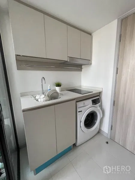 公寓 出租在Sathon, Bangkok - 明亮小厨房，水槽、电磁炉、顶柜与前置式洗衣机。