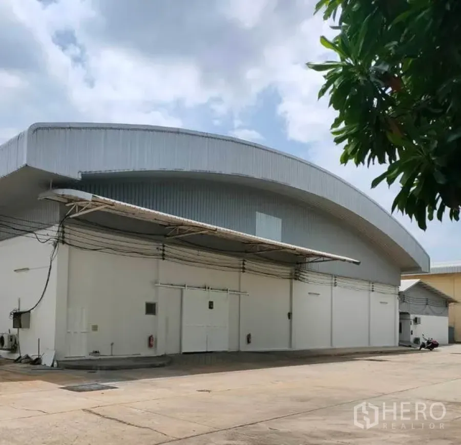 货栈 出租在Bang Pa-in, Phra Nakhon Si Ayutthaya - 白色弧形屋顶仓库外观，带雨棚与宽阔混凝土堆场。