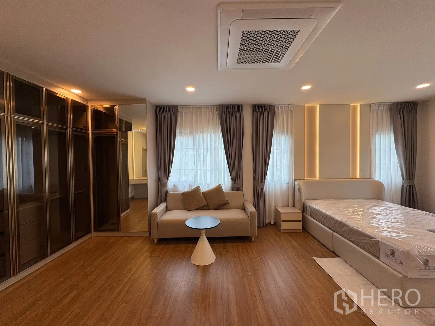 Detached House for rent in Bang Phli, Samut Prakan - Master bedroom view with glass-door wardrobes, sofa and warm ambient lighting.