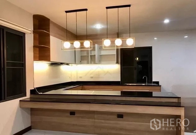 Home Office for rent in Watthana, Bangkok - Contemporary U‑shaped kitchen with wood cabinetry, black countertops, mirrored backsplash and pendant lights.