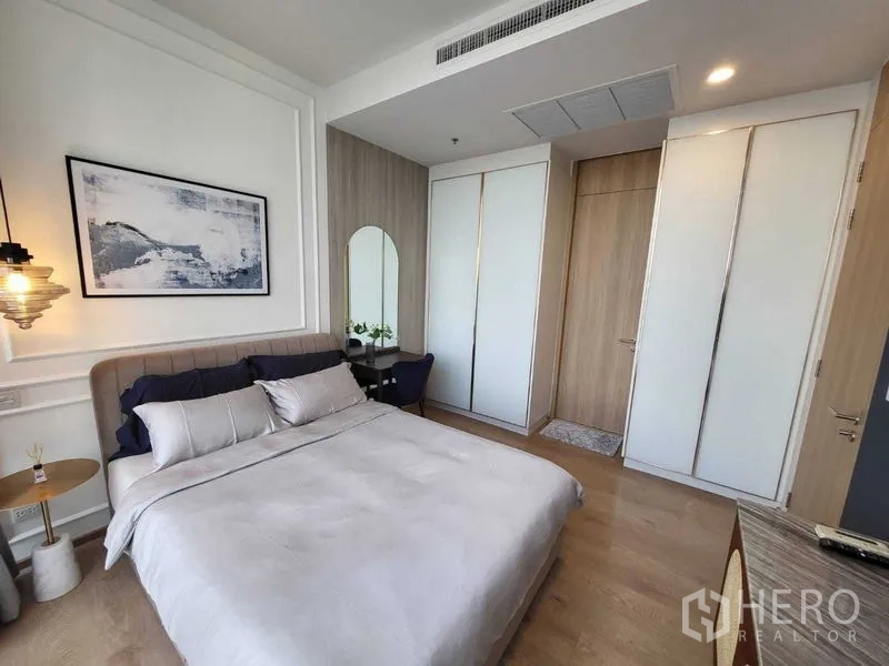 Condominium for rent in Watthana, Bangkok - Bedroom in neutral tones featuring full‑height wardrobes, dressing table and warm wood floors.