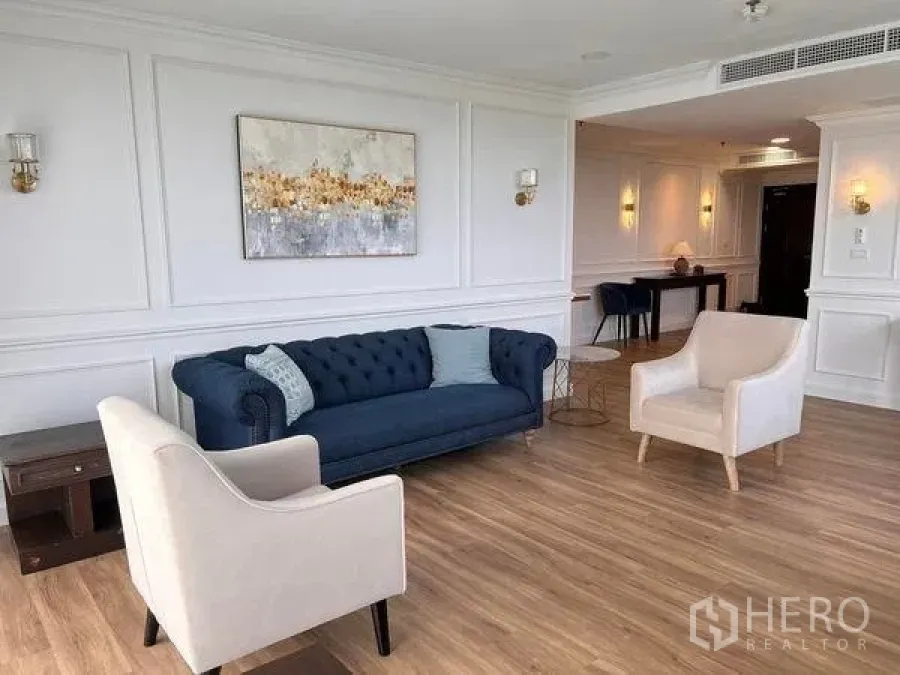 คอนโด ให้เช่าในKhlong Toei, Bangkok - ห้องนั่งเล่นสว่าง โซฟากำมะหยี่สีน้ำเงิน เก้าอี้สองตัว และผนังบัวสวยงาม