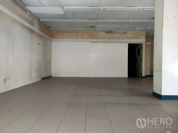 零售空间 出租在Khlong Toei, Bangkok - 店铺后方墙面与门洞，瓷砖地面与条形灯。