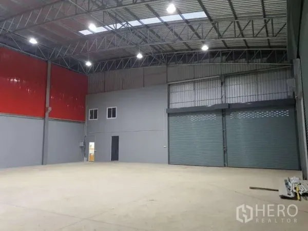 货栈 出租在Khlong Luang, Pathum Thani - 开阔仓库空间，红色金属墙面，双宽幅卷闸门及小型办公区。