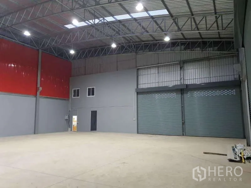 货栈 出租在Khlong Luang, Pathum Thani - 开阔仓库空间，红色金属墙面，双宽幅卷闸门及小型办公区。