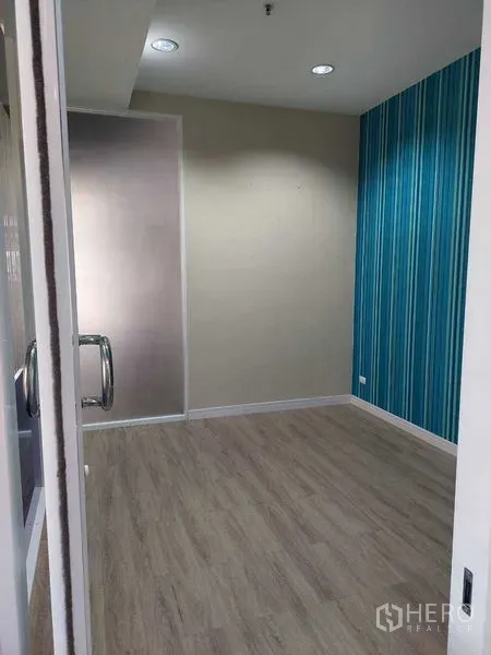 Retail Space for rent in Sathon, Bangkok - Retail unit interior with wood-look flooring, blue striped accent wall and a glass door entry.