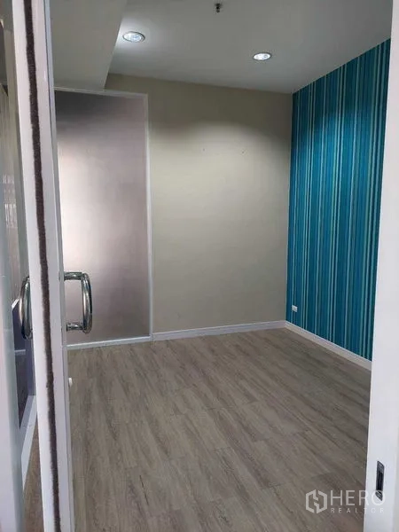 Retail Space for rent in Sathon, Bangkok - Retail unit interior with wood-look flooring, blue striped accent wall and a glass door entry.