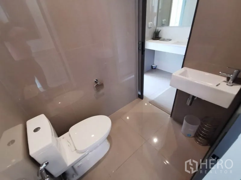 Condominium for rent in Khlong Toei, Bangkok - Clean guest WC with wall-mounted sink leading to separate vanity area.