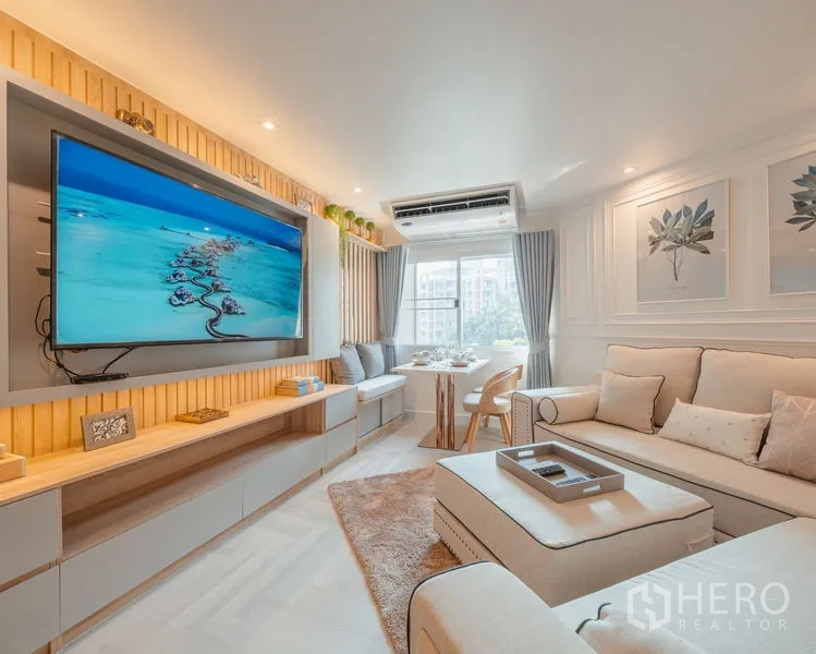 Condominium for sale in Yan Nawa, Bangkok - Living area with large TV feature wall, sofa set, and dining table by the window.