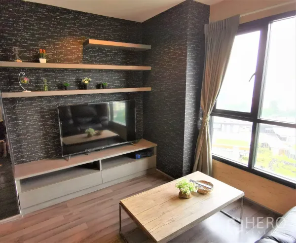 公寓 出租或出售在Watthana, Bangkok - 带置物层板的电视墙，旁有窗户与茶几。