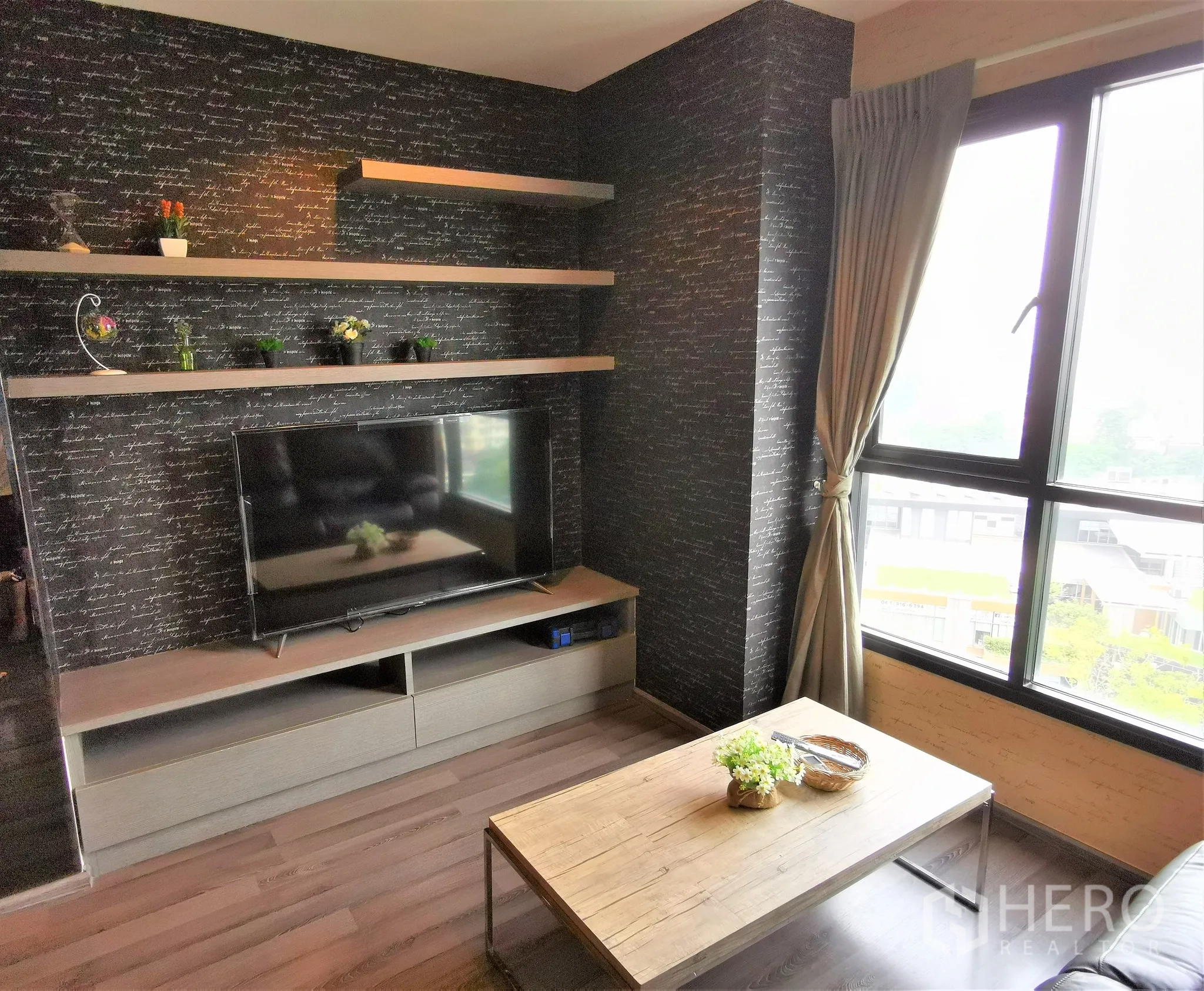 公寓 出租或出售在Watthana, Bangkok - 带置物层板的电视墙，旁有窗户与茶几。
