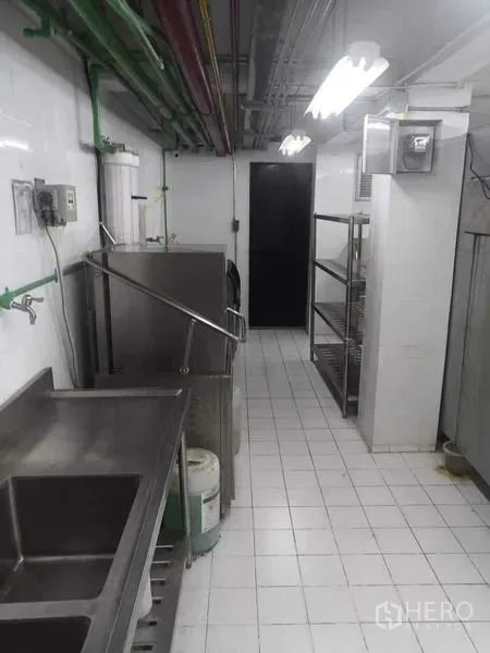 零售空间 出租在Watthana, Bangkok - 商业后厨走道，含不锈钢水槽、置物架与瓷砖地面。