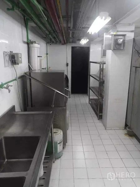 零售空间 出租在Watthana, Bangkok - 商业后厨走道，含不锈钢水槽、置物架与瓷砖地面。