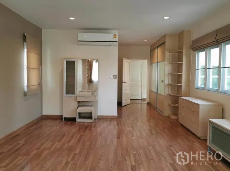 Detached House for rent in Bang Kapi, Bangkok - Spacious master bedroom with wood flooring, built‑in wardrobes, dressing table and air conditioning.