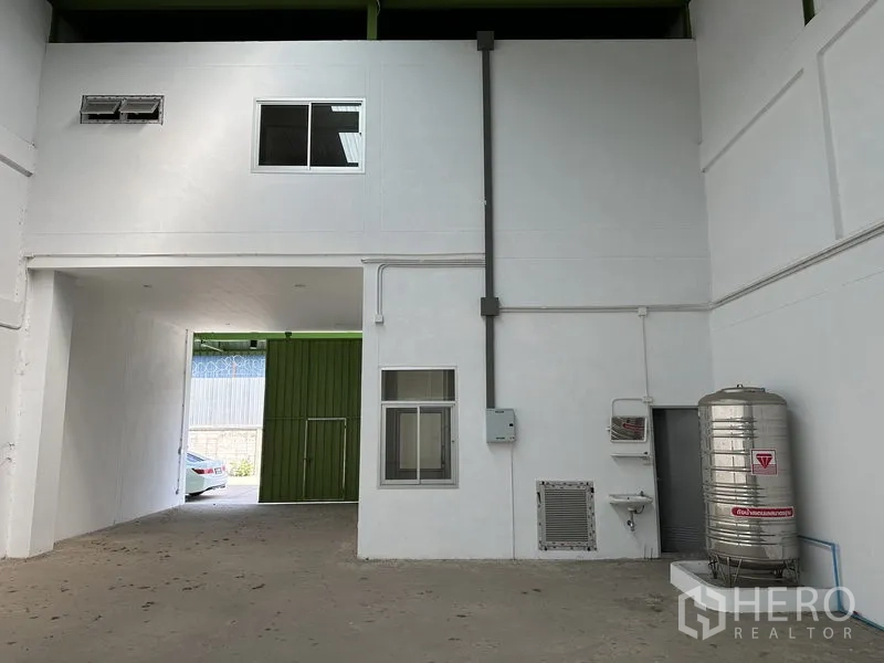 Warehouse for rent in Pathum Thani - Utility wall with mezzanine office windows, stainless water tank and service sink.
