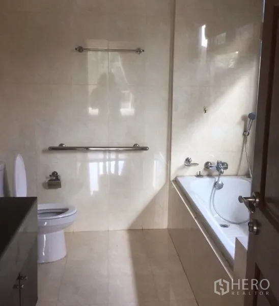 Detached House for rent in Bang Phli, Samut Prakan - Bathroom with beige tiles featuring a bathtub, handheld shower and grab bars.