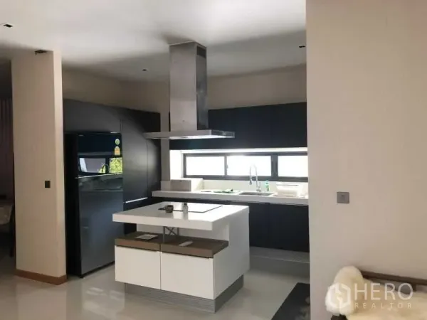 Detached House for rent or sale in Huai Khwang, Bangkok - Sleek kitchen with a central island cooktop, stainless range hood, dark cabinetry and a long horizontal window.