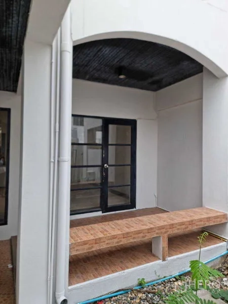 ทาวน์เฮาส์ ให้เช่าในWang Thonglang, Bangkok - ด้านหน้าทาวน์เฮาส์สามชั้นสีขาว มีระเบียง ประตูรั้วไม้ และที่จอดรถในบ้าน