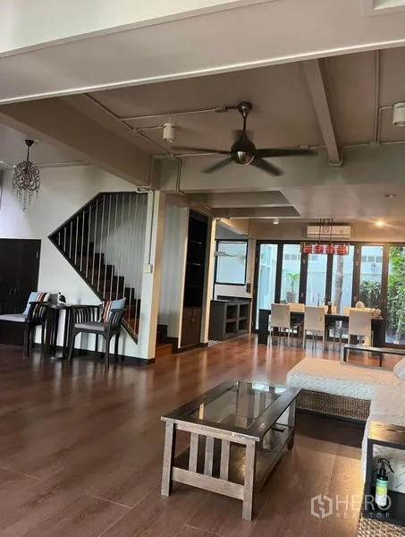Townhouse for rent in Phaya Thai, Bangkok - Large living and dining space with ceiling fan, sofa and glass doors to patio greenery.