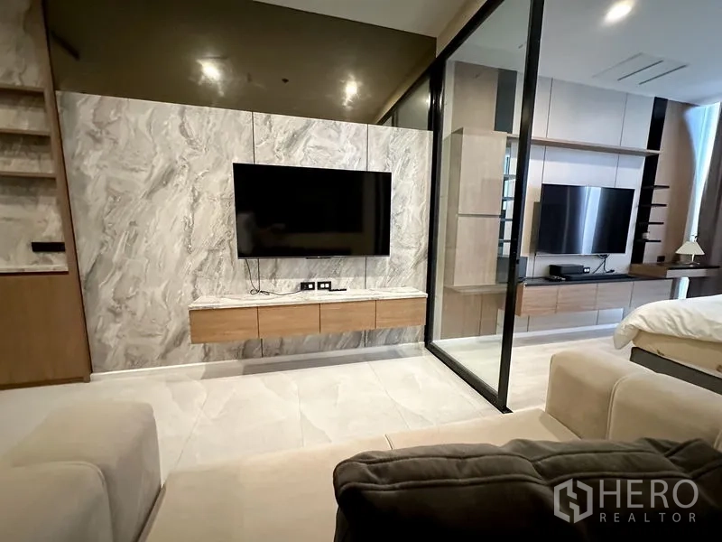 คอนโด ให้เช่าในPathum Wan, Bangkok - ห้องนั่งเล่นและห้องนอนกั้นด้วยประตูกระจกบานเลื่อน ทั้งสองห้องมีชั้นวางทีวีบิวท์อิน