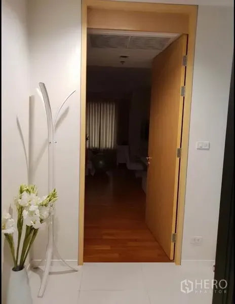 公寓 出租在Sathon, Bangkok - 入户走廊，木门开启，白色地砖与装饰花瓶。