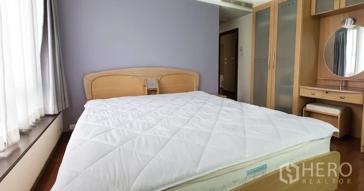 Condominium for rent in Sathon, Bangkok - Primary bedroom with queen bed, wardrobes and dressing table by a large window.