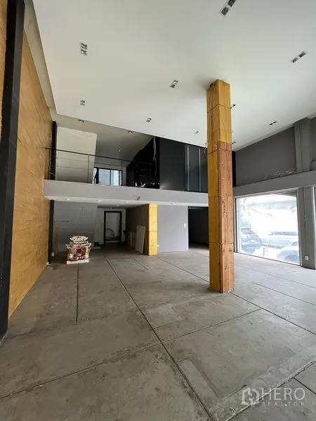 店屋 出租在Watthana, Bangkok - 展厅带夹层，挑高天花、整面落地窗与中央立柱。