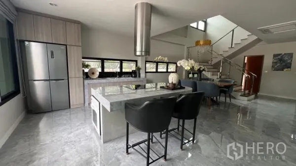 บ้าน ให้เช่าในLat Krabang, Bangkok - ครัวเปิดพร้อมไอส์แลนด์หินอ่อน เครื่องดูดควัน และเก้าอี้บาร์ เชื่อมต่อบันได