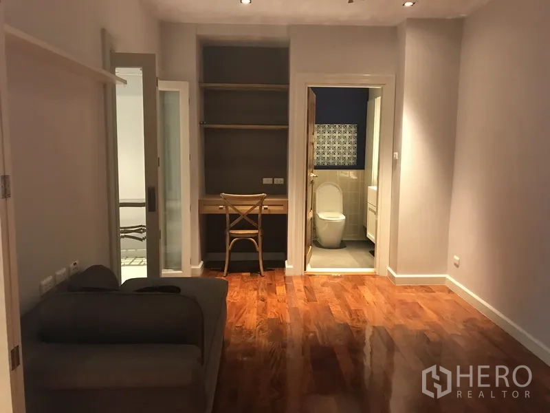 Apartment for rent in Pathum Wan, Bangkok - Guest bedroom with study nook, shelving and ensuite bathroom access.