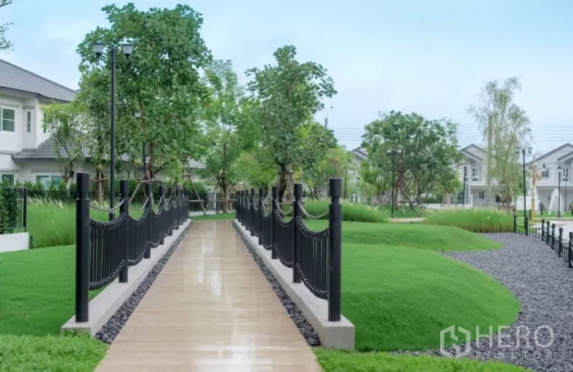Townhouse for rent in Bang Phli, Samut Prakan - Leafy community park with pathway, manicured lawns and black railings.
