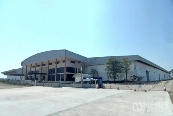 Warehouse for rent in Bang Pakong, Chachoengsao - Angled exterior view of the warehouse with truck access road and spacious paved yard.