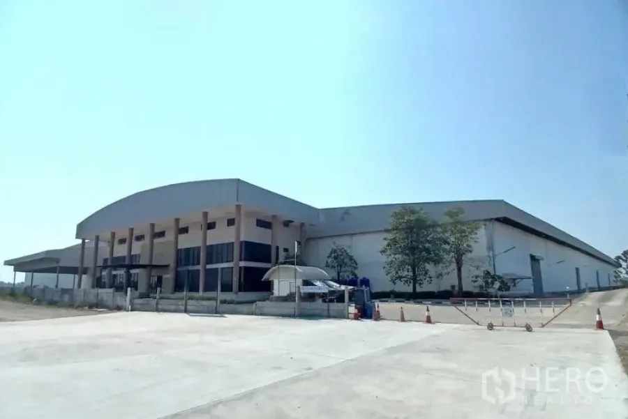Warehouse for rent in Bang Pakong, Chachoengsao - Angled exterior view of the warehouse with truck access road and spacious paved yard.