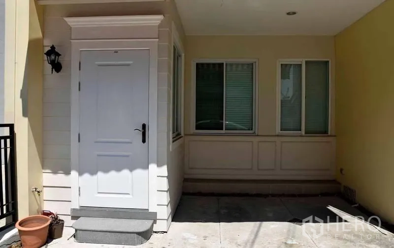 联排别墅 出租或出售在Wang Thonglang, Bangkok - 联排别墅的有顶入口与小车位，白色入户门与窗户。