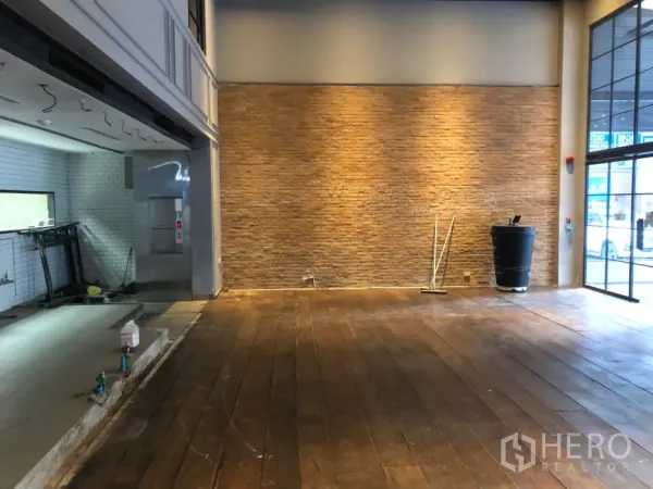 พื้นที่ขายปลีก ให้เช่าในKhlong Toei, Bangkok - โถงเปิดโล่ง ผนังอิฐโชว์ ไฟส่องผนัง และพื้นไม้ใกล้หน้าร้าน