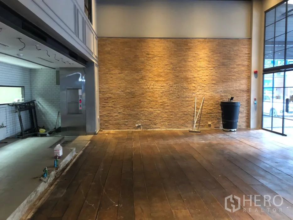 พื้นที่ขายปลีก ให้เช่าในKhlong Toei, Bangkok - โถงเปิดโล่ง ผนังอิฐโชว์ ไฟส่องผนัง และพื้นไม้ใกล้หน้าร้าน