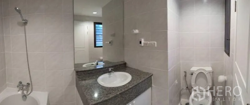 Condominium for rent in Sathon, Bangkok - Bright tiled bathroom with bathtub, granite vanity and large mirror in Sathon condo.