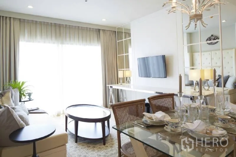 公寓 出租在Bangkok - 起居区朝向大窗，电视墙与镜面装饰，旁连餐区