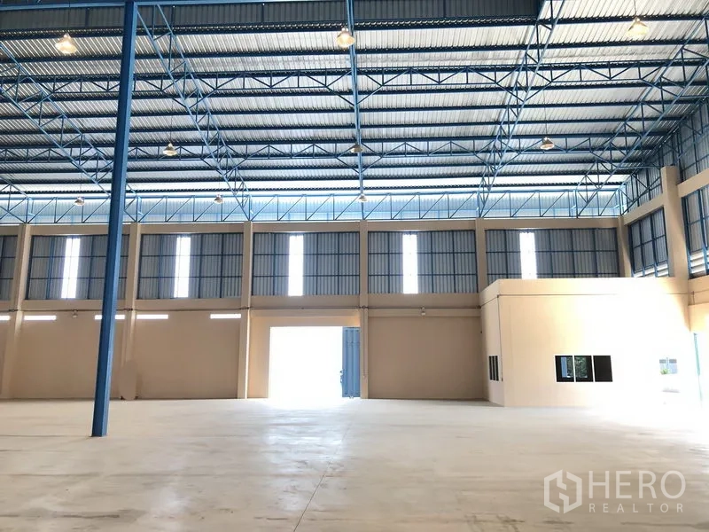 Warehouse for rent in Lat Lum Kaeo, Pathum Thani - Interior showing large roller doors and an integrated office block inside the warehouse.