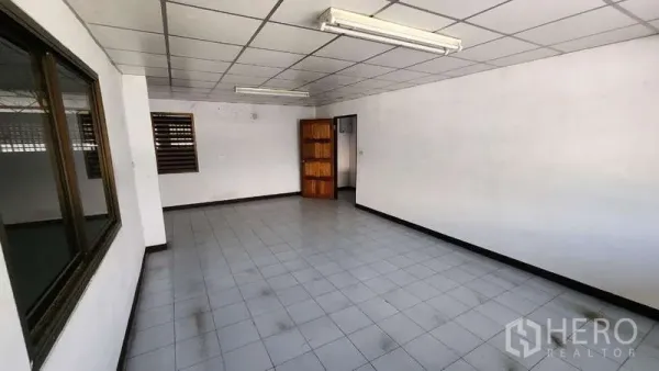 Warehouse for rent in Nong Khaem, Bangkok - Open plan office space with ceiling lights, windows, and doorway to ancillary rooms.