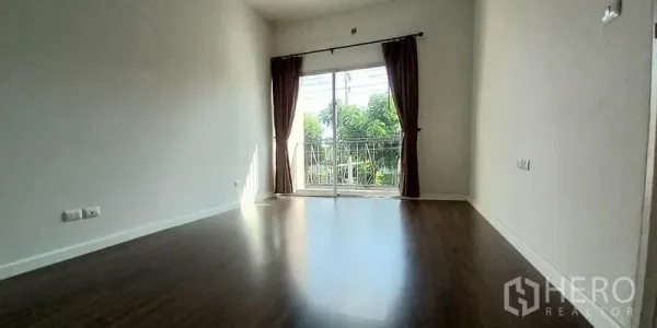 ทาวน์เฮาส์ ขายในMueang Pathum Thani, Pathum Thani - ห้องชั้นบนสว่าง พื้นไม้ พร้อมประตูกระจกบานเลื่อนไปยังระเบียงเล็ก