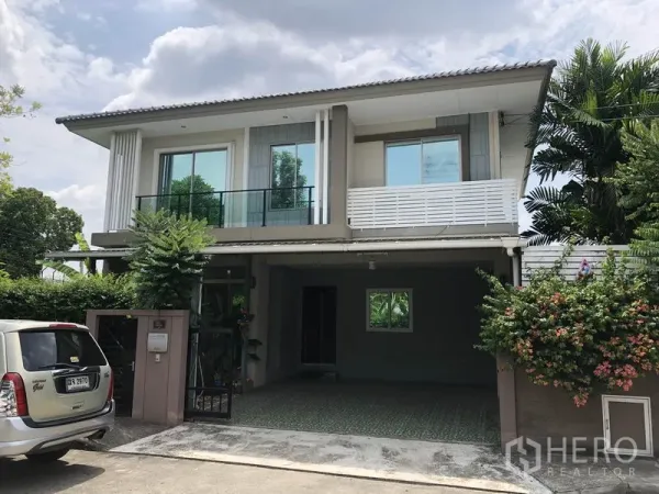 บ้าน ให้เช่าในSuan Luang, Bangkok - ด้านหน้าบ้านเดี่ยวสองชั้นพร้อมระเบียง ประตูรั้ว และต้นไม้ร่มรื่น