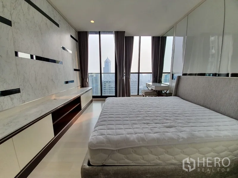 Condominium for rent in Pathum Wan, Bangkok - Bedroom with panoramic city views, built-in wall console and full-height windows.