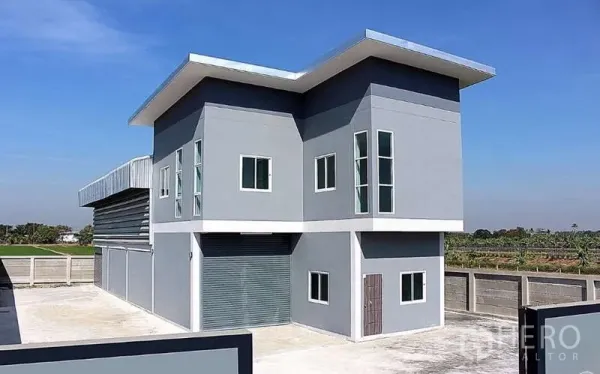 คลังสินค้า ขายในPathum Thani - ภาพภายนอกโกดังพร้อมอาคารสำนักงาน 2 ชั้น ประตูม้วน และลานคอนกรีตกว้าง