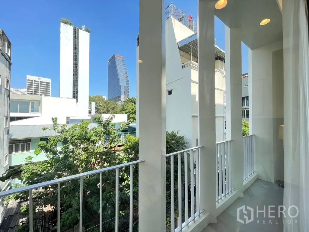 Townhouse for rent - Bedroom balcony view of mature trees and surrounding low-rise buildings.